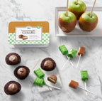 Caramel apples and candy on sticks with a packaging box on a marble surface