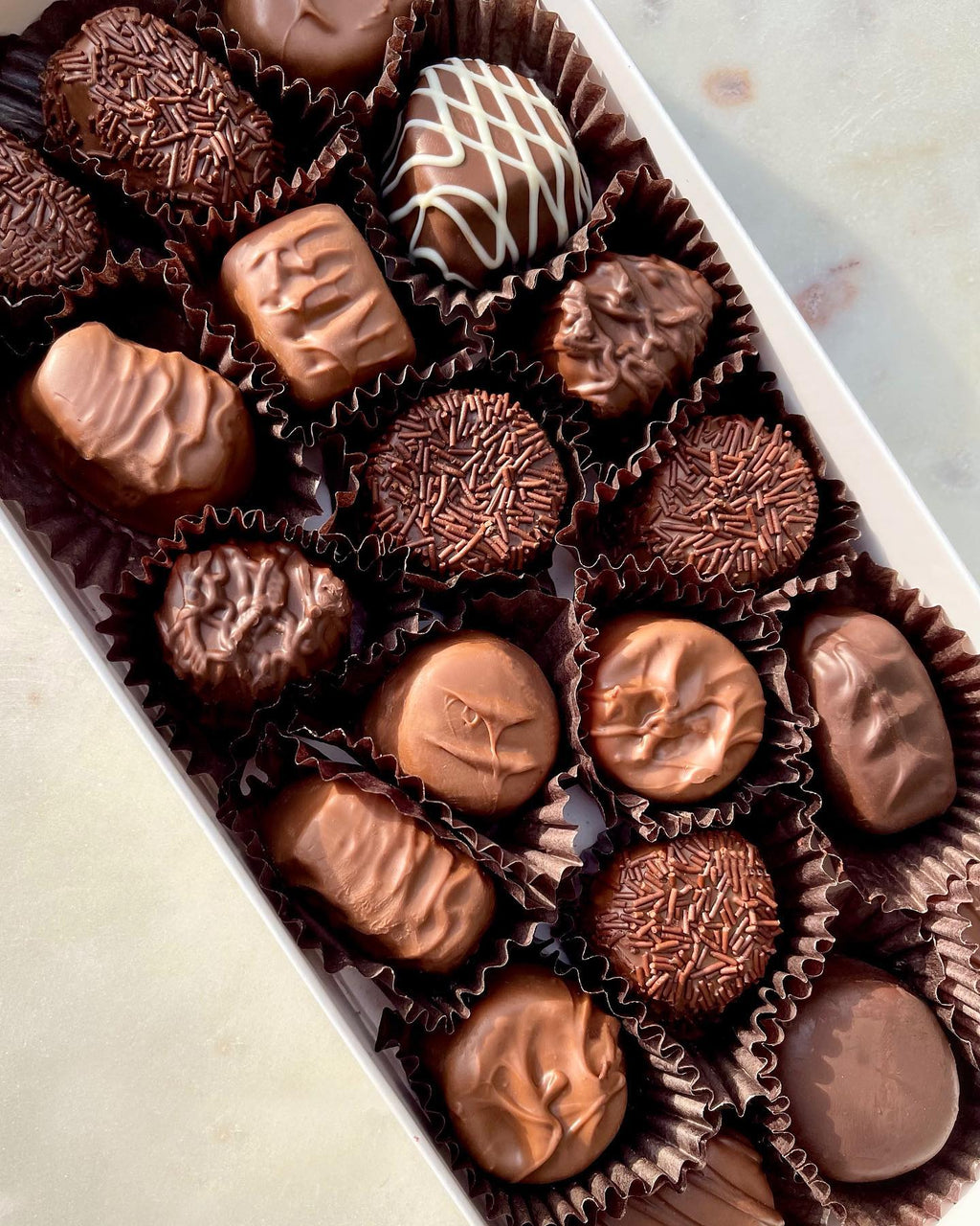 Assorted chocolate candies in a box on a light background