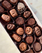 Assorted chocolate candies in a box on a light background
