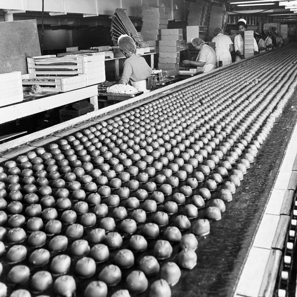 Soft center chocolates on a conveyor belt with workers in a factory setting