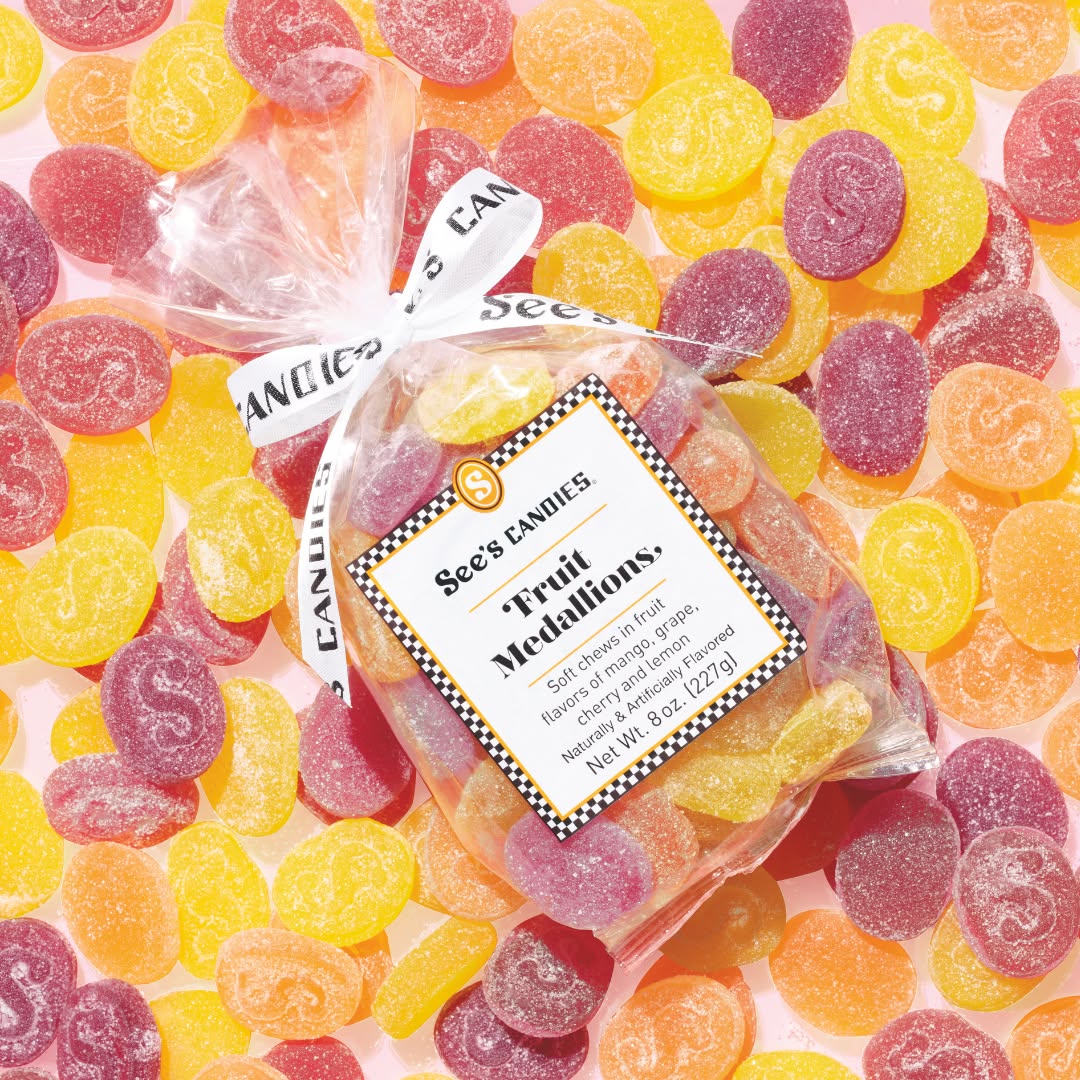 Packaged See's fruit gummies with a label on a bed of colorful gummy candies.