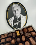 Box of chocolates with a framed portrait of an Mary See woman in the background