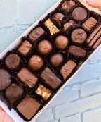 Box of assorted chocolates on a light blue brick background