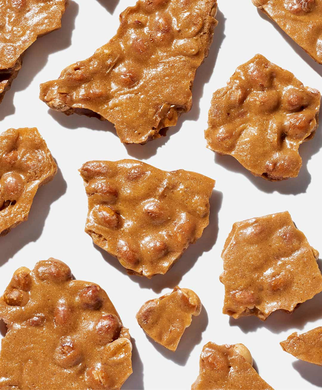 Close-up of peanut brittle pieces on a white background