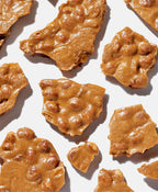 Close-up of peanut brittle pieces on a white background