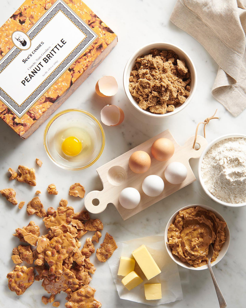 Peanut brittle with ingredients on a marble surface
