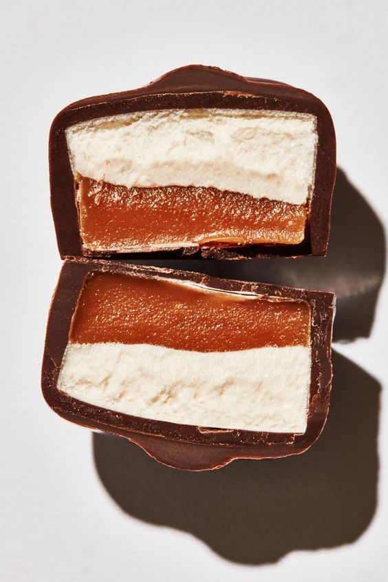 Close-up of a chocolate-covered dark Scotchmallow layered dessert on a white background