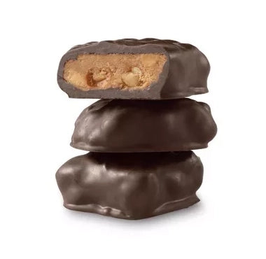 Stack of chocolate-covered peanut crunch with one cut open to reveal a filling on a white background
