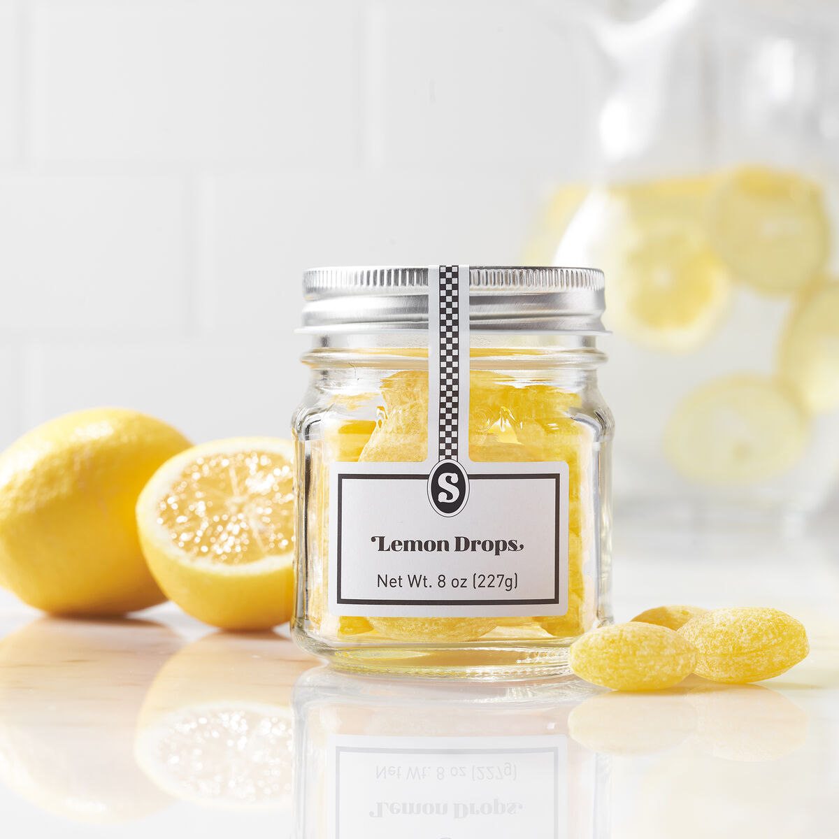 Jar of lemon drops with lemons on a light background