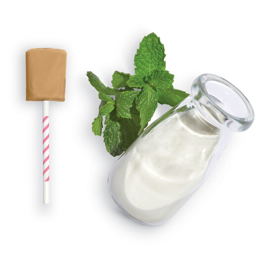 Bottle of white liquid with a wooden dropper, mint leaves, and a straw on a white background