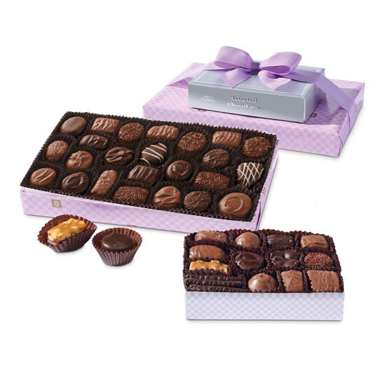 Assorted chocolates in a decorative box with a purple ribbon on a white background