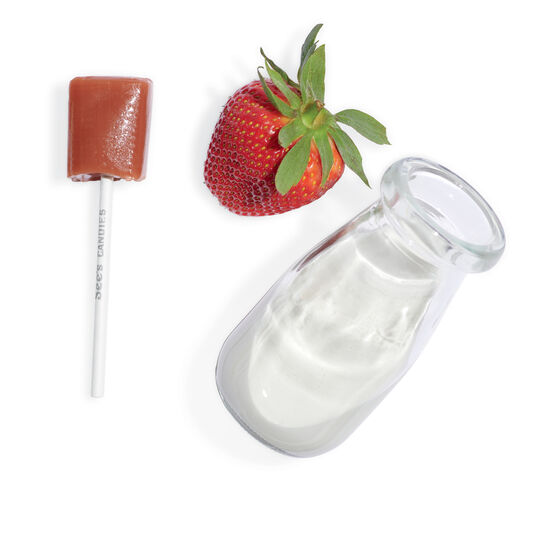 Glass bottle, strawberry, and brown lollipop on a white background