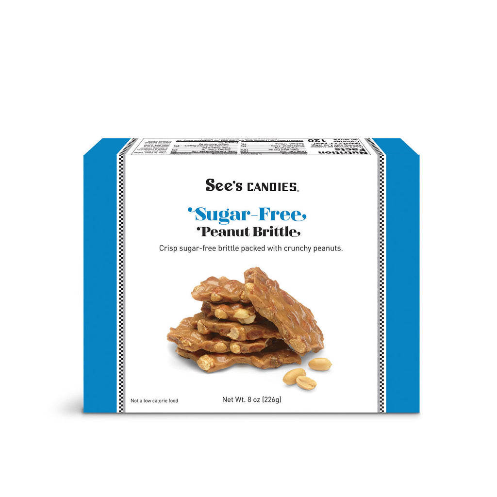 A box of See's Candies Sugar-Free Peanut Brittle on a plain white background. The packaging features a white front with a blue side border, showing an image of the golden-brown brittle cookies with peanuts.