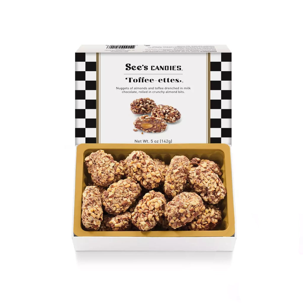 An open box of See's Candies Toffee-ettes, showing several coated toffee pieces in a gold tray, with the branded white lid behind it on a clean white background.